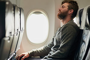 man with closed eyes in airline seat